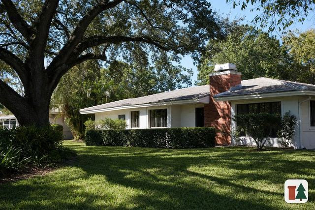 Ranch house with a brick chimney and metal cap under a live oak
